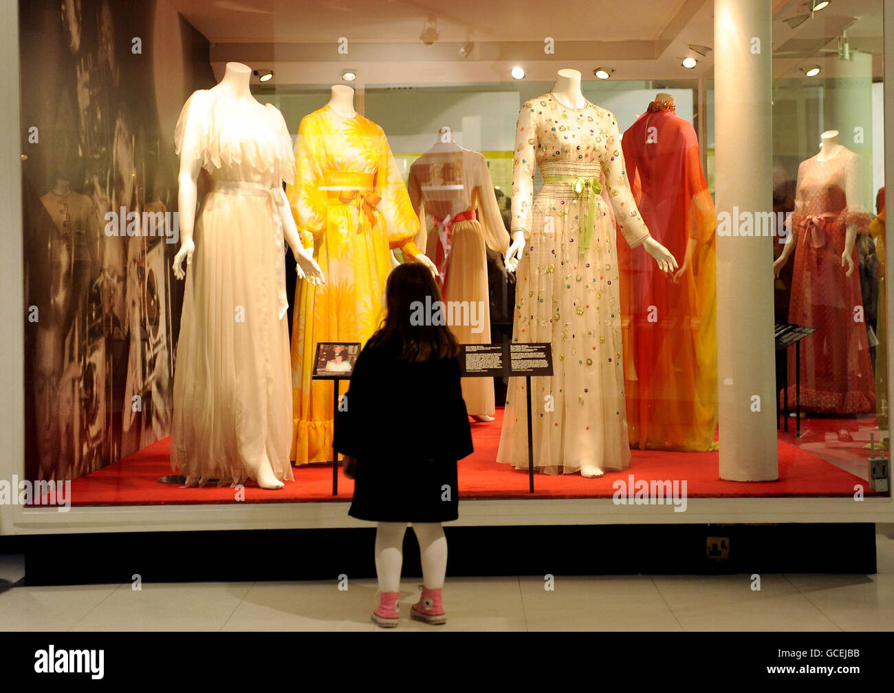 A young girl looks at dresses as the wardrobe of Hollywood icon Grace Kelly goes on show as part of the Grace Kelly: Style Icon exhibition at the Victoria and Albert Museum, London. Stock Photo