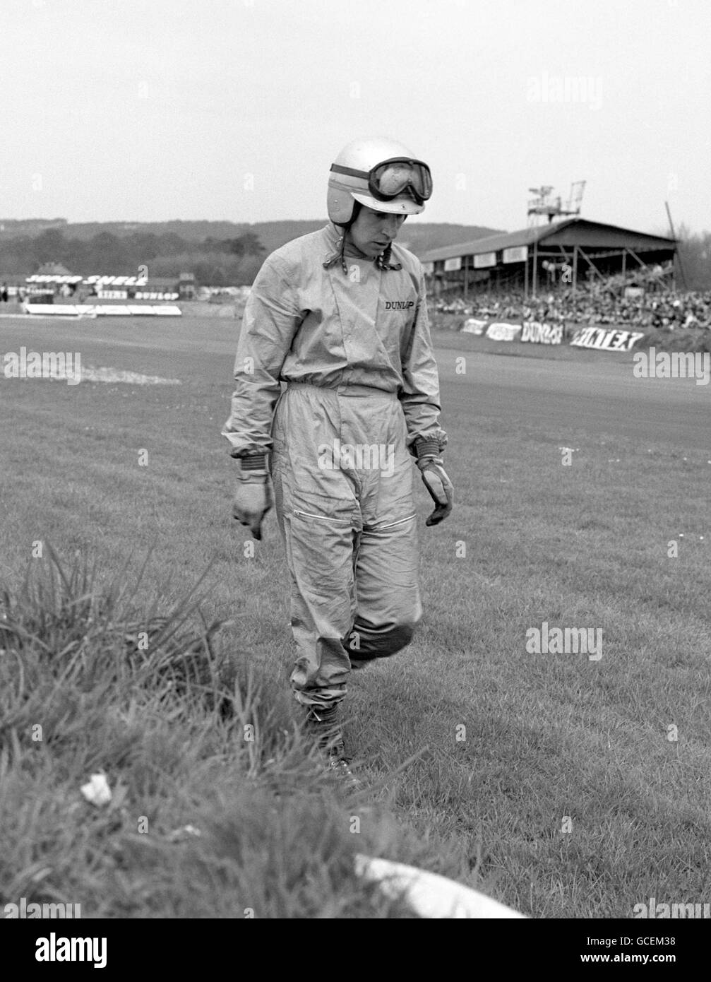 John Surtees, former world champion motorcyclist and now a car racer, walks away unhurt after a crash in the Lavant Cup event at the International Motor Racing meeting at Goodwood. Stock Photo