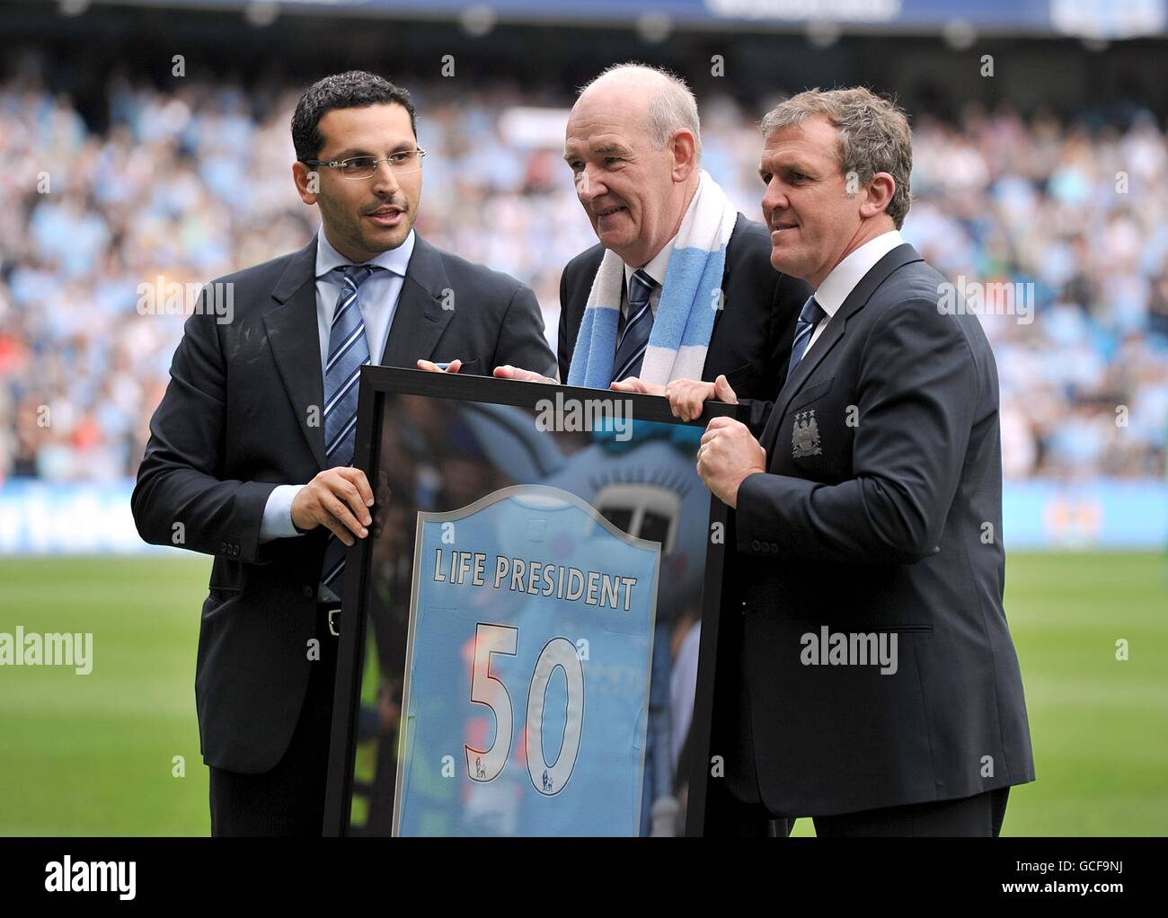 Long-serving club secretary Bernard Halford (centre) is presented a shirt by Manchester City's Chairman Khaldoon Al Mubarak (left) and Executive Chairman Garry Cook (right), becoming only the second Life President in the club's 116-year history Stock Photo