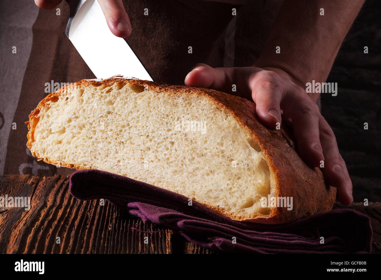 Baker cutting and holding fresh made bread  isolated on white background. Baker and bakery, rustic styles. Stock Photo