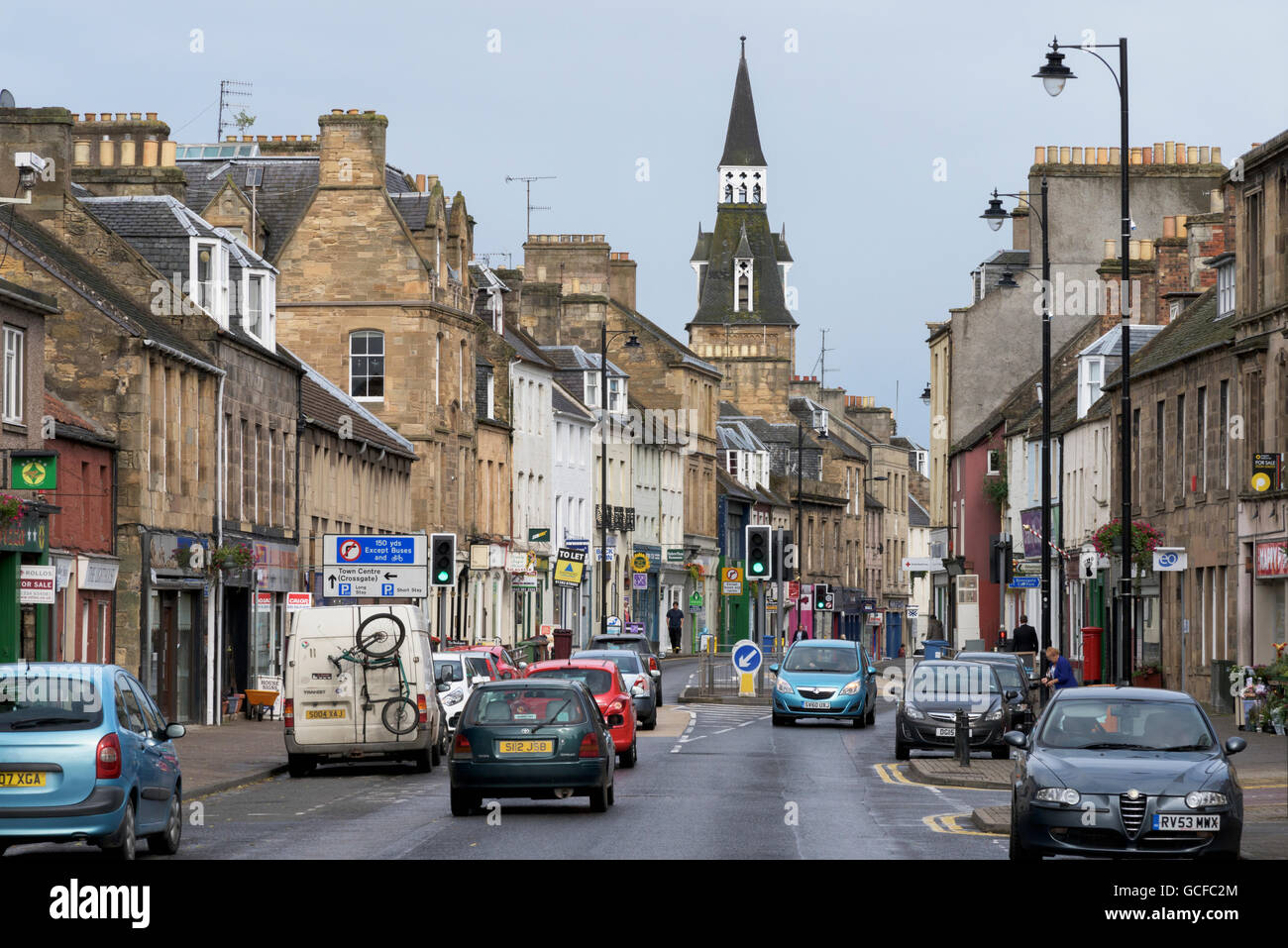 A busy street with traffic, buildings and a tower against a cloudy sky; Cupar, Fife, Scotland Stock Photo