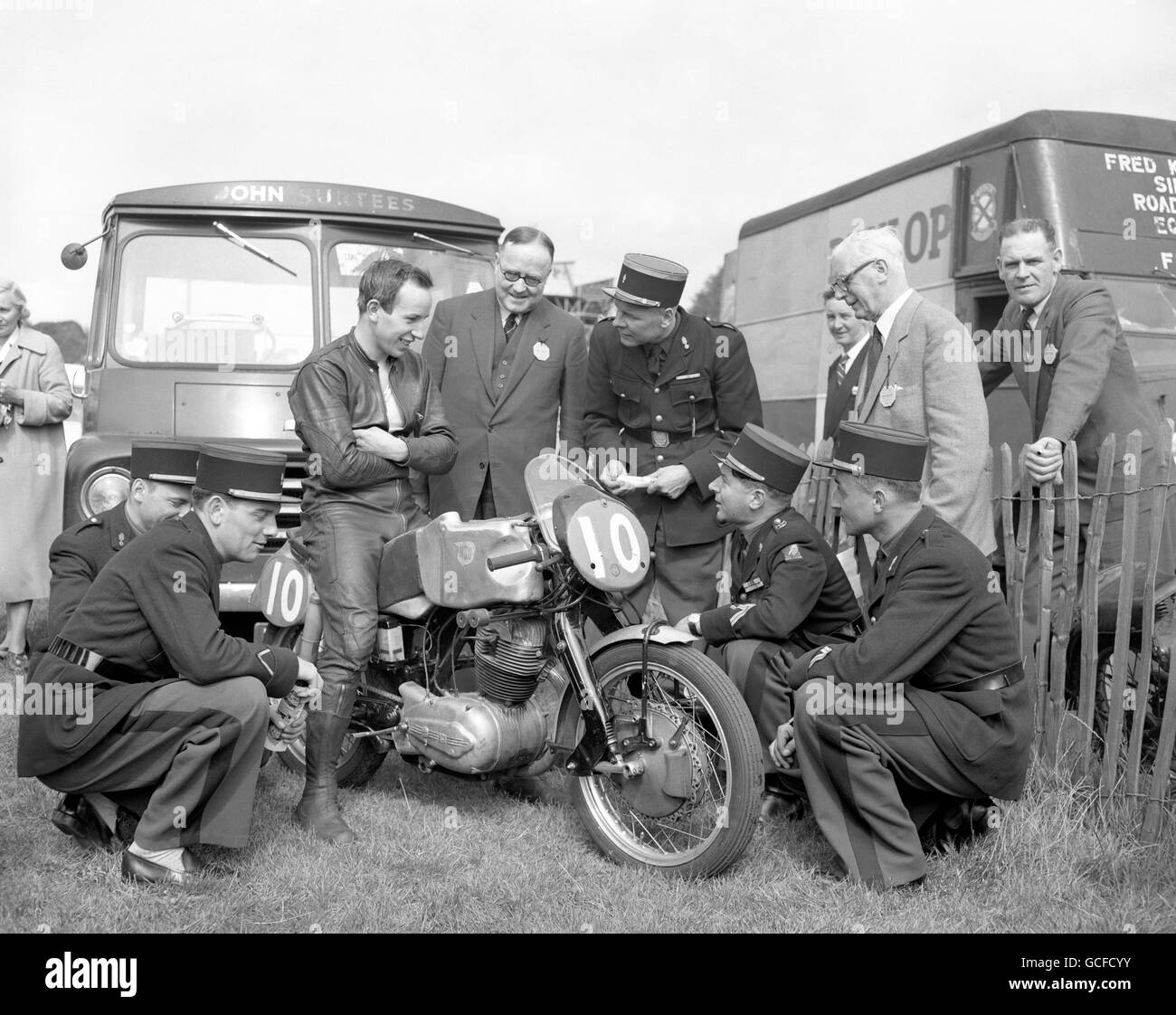 An expert and admiring group of French motorcyclists, from the Garde Republicaine de Paris, gathers around world motor cycling champion John Surtees and his machine at the motorcycling race meeting at Crystal Palace. The Frenchmen, who are taking part in the White City Searchlight Tattoo, are the motorcycle escort for the French President and distinguished visitors to Paris. Stock Photo