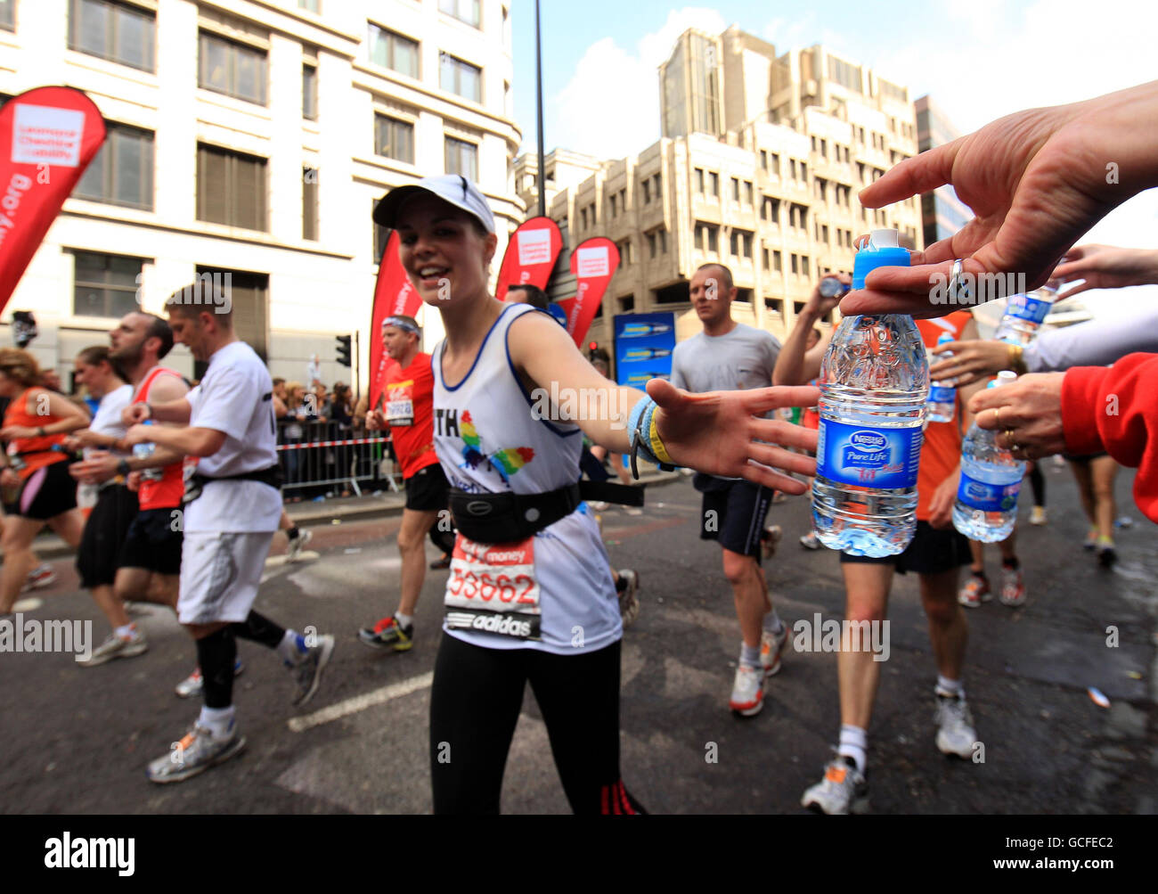 A water bottle is handed out to a participant during the 2010 Virgin London Marathon, London. Stock Photo