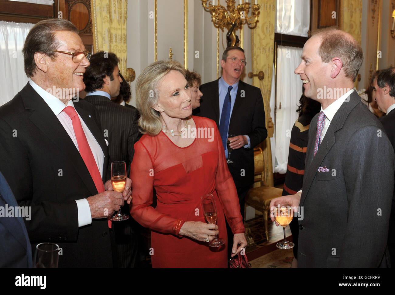 The Earl of Wessex (right) talks with Sir Roger Moore and his wife Kristina, at a drinks reception for the 'Film without Borders' charity at Buckingham Palace in central London. Stock Photo