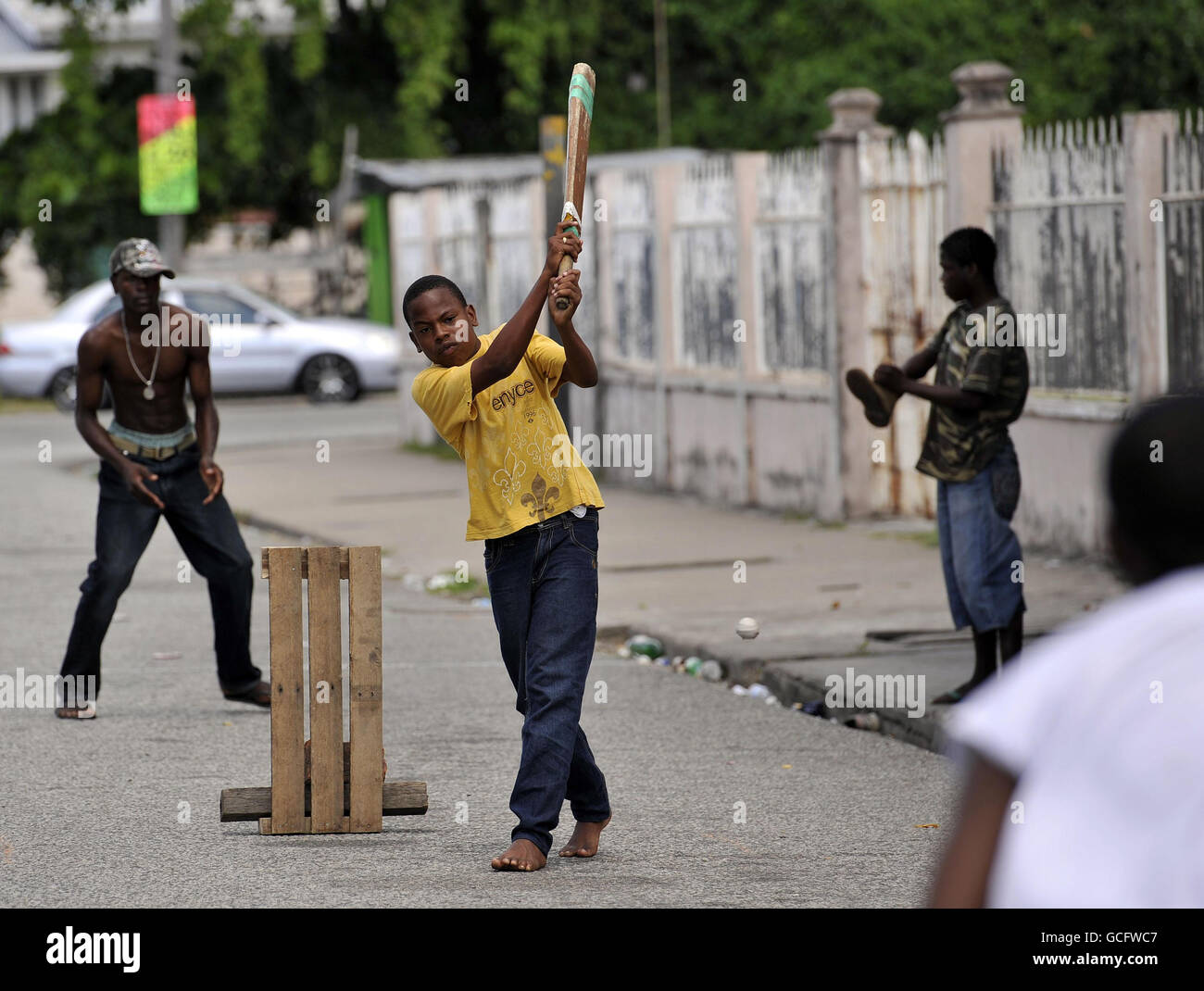 A young boy bats in a street cricket match in Georgetown, Guyana. Stock Photo