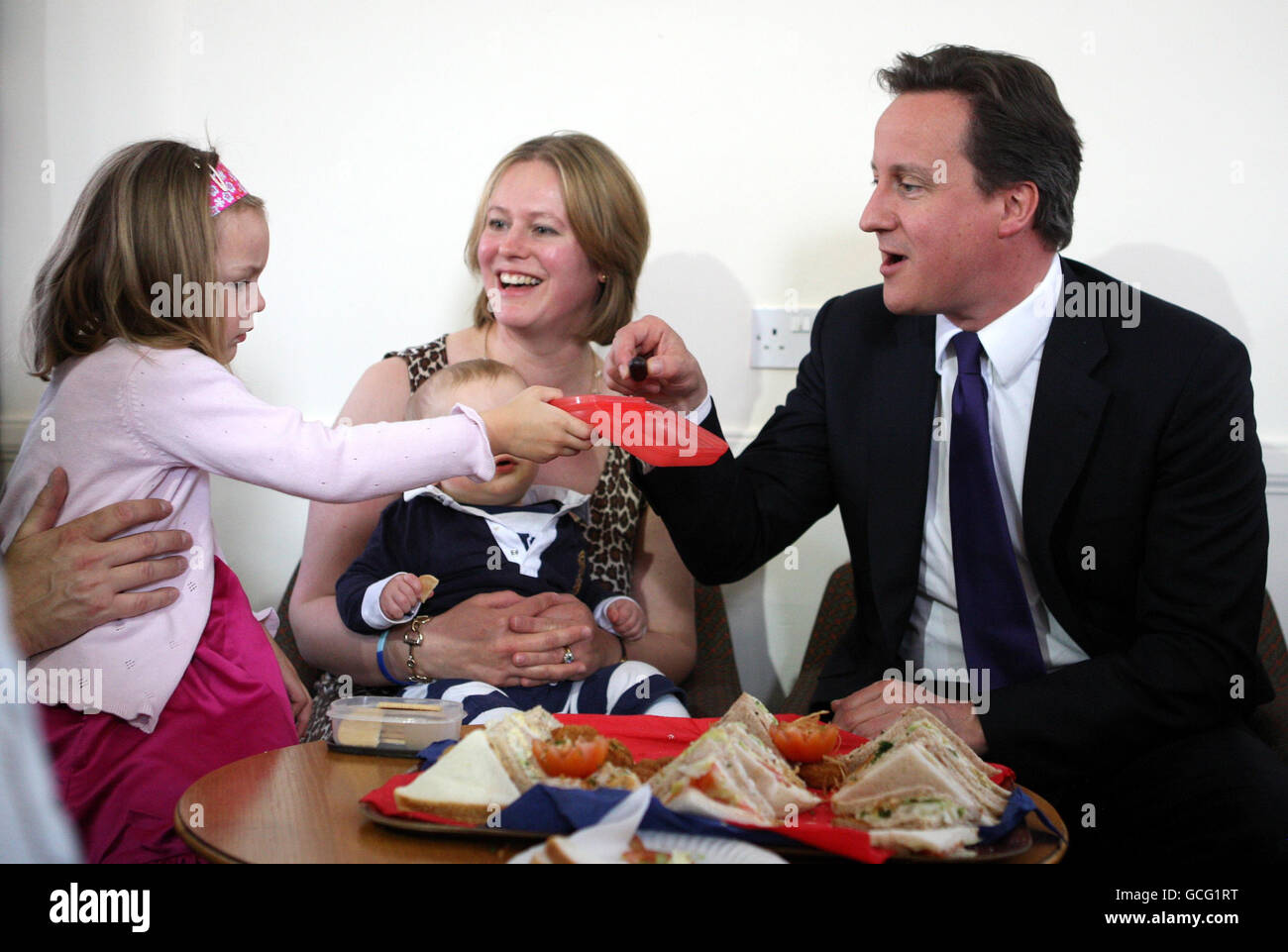 Prime Minister David Cameron accepts the offer of a grape from Emma-Louise Rawlings, 4, from Inverness, during a visit to Fort George near Inverness, where he met soldiers from the Black Watch 3rd Battalion The Royal Regiment of Scotland and their families. Stock Photo