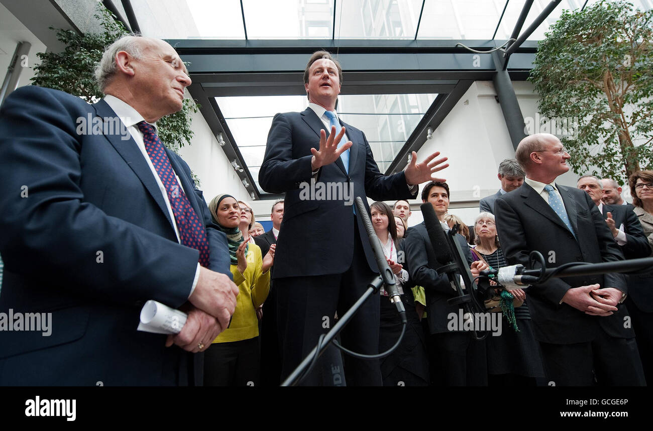 Britain's new Business Secretary, Vince Cable (left), and Minister of State for Universities and Science, David Willetts (right) listen as Prime Minister David Cameron speaks during an official visit to the Department for Business, Innovation and Skills in central London. Stock Photo