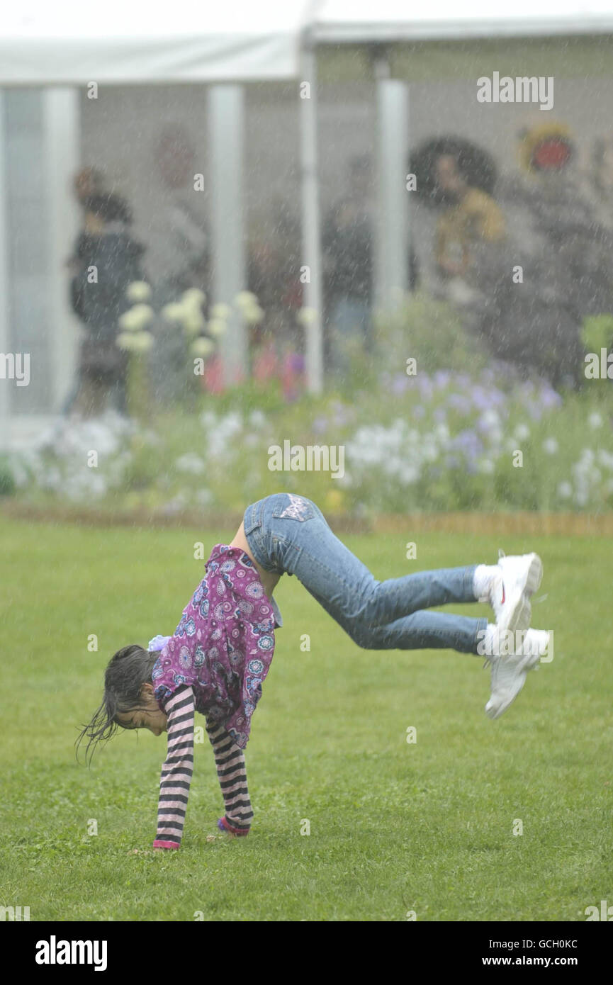 Hay Festival. A girl plays in a very heavy downpour as showers come and go at the Hay Festival in Hay-on-Wye. Stock Photo