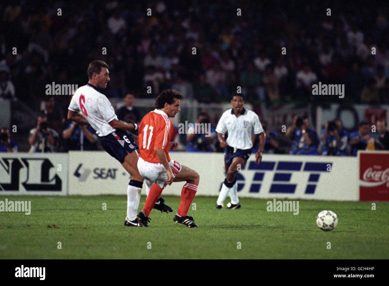 Soccer - FIFA World Cup Italia 90 - Group F - England v Netherlands - Stadio Sant'Elia, Cagliari. England's Terry Butcher plays the ball under pressure from the Netherlands' Hans Gillhaus. England's Des Walker is in the background. Stock Photo
