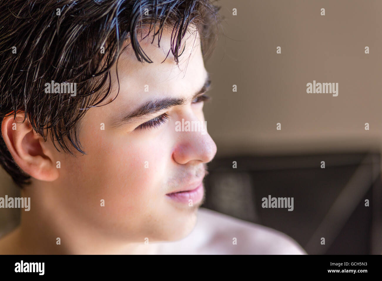 close up of sideview of face of young teen boy in profile in interiors under harsh sun light Stock Photo