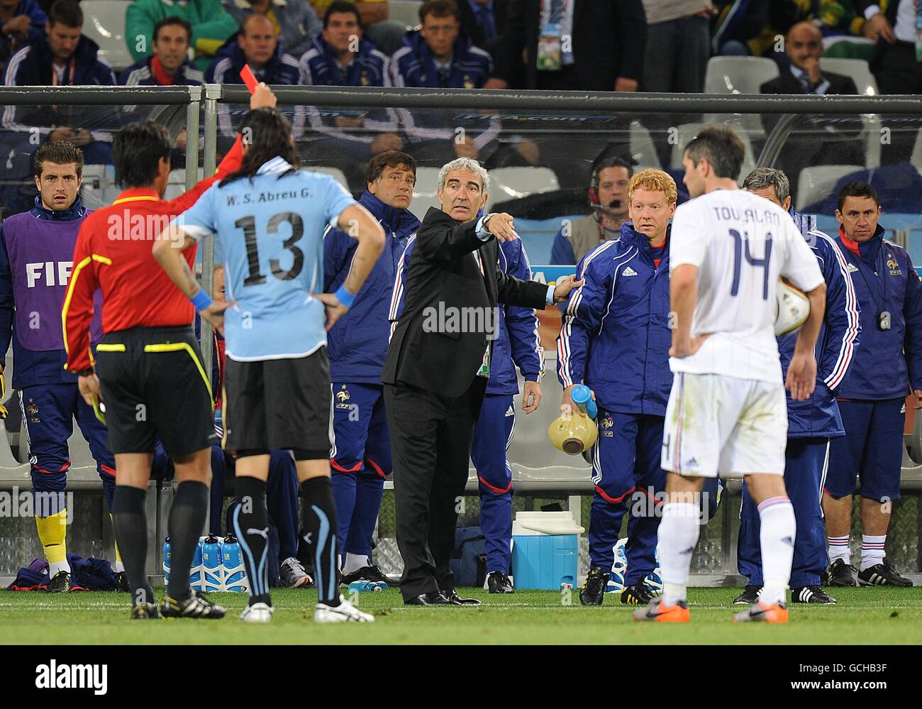 France's coach Raymond Domenech (centre) watches as referee Yuici Nishimura (left) shows Uruguay's Nicolas Lodeiro (not in picture) the red card. Stock Photo