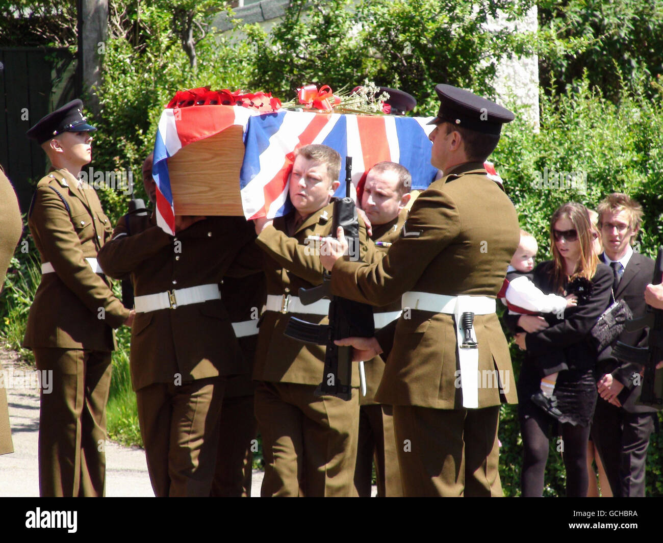The coffin of Signalman David Grout is carried into Christ Church, Eston, Teesside, followed by his widow Kerry carrying their 20-month-old son Harley during his full military funeral. Stock Photo