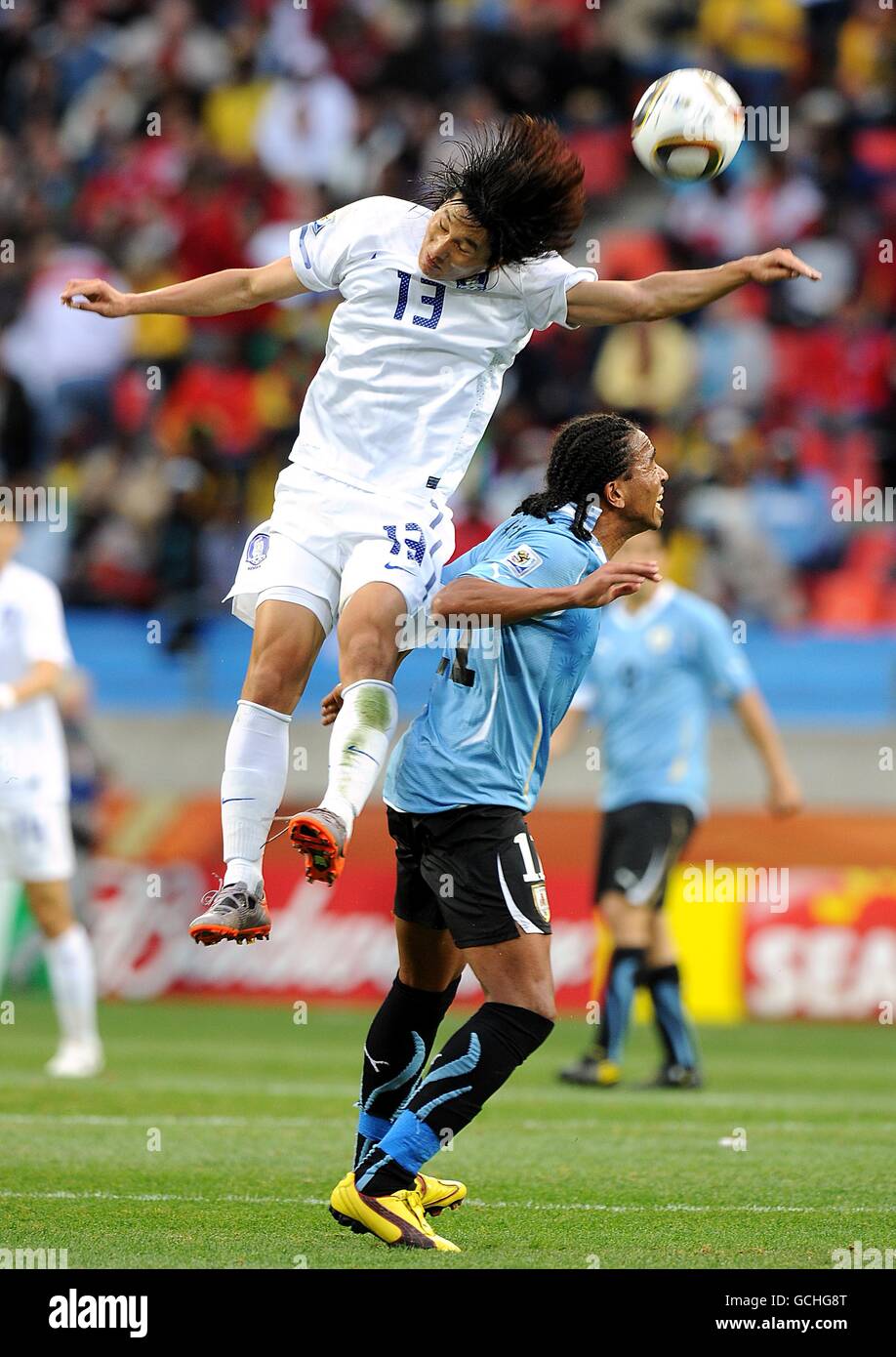 South Korea's Jae-Sung Kim (left) beats Uruguay's Alvaro Pereira to the ball Stock Photo