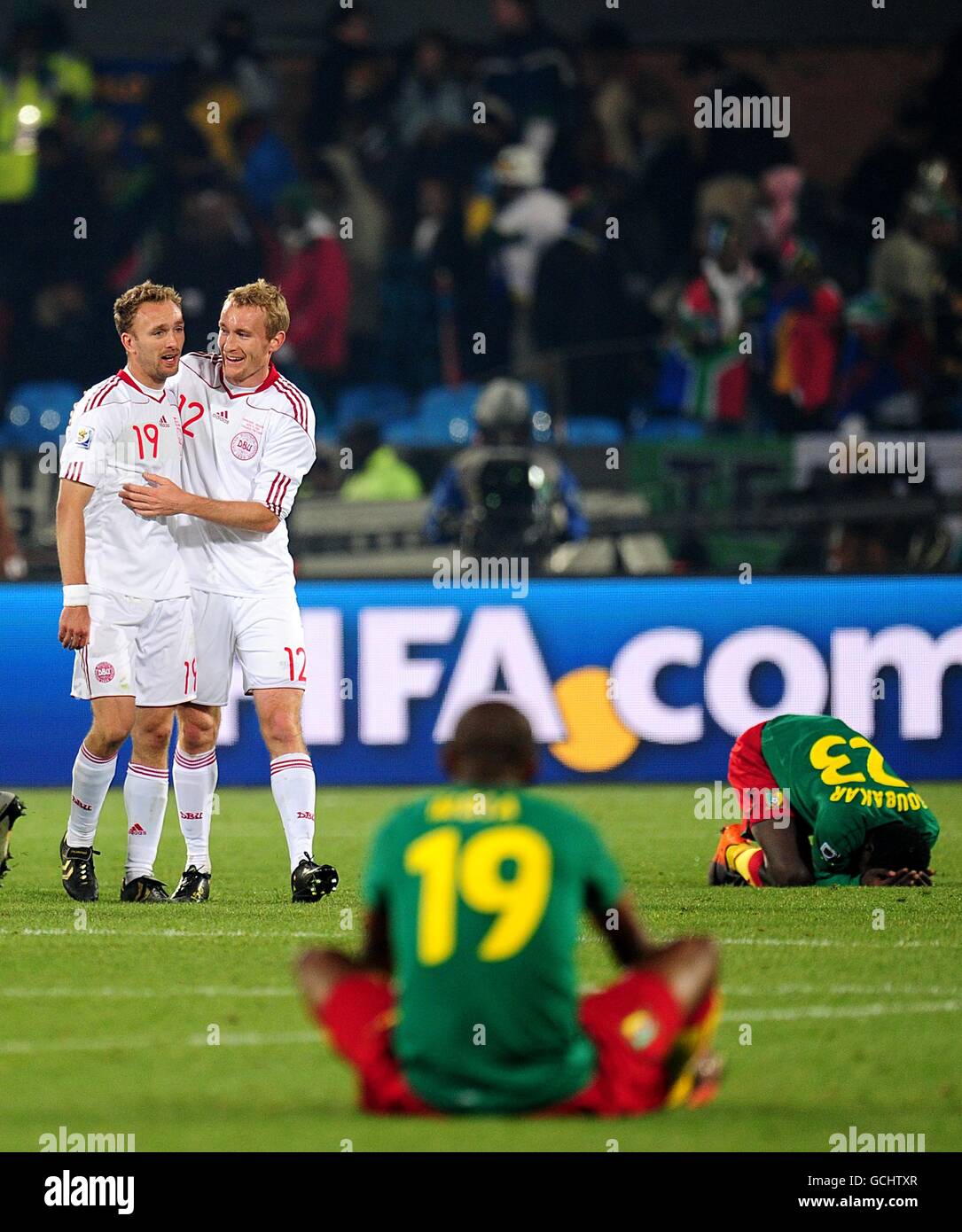 Cameroon's Stephane M'bia Etoundi (19) and Vincent Aboubakar (far right) dejected as Denmark's Thomas Kahlenberg (12) and Dennis Rommedahl (left) celebrate victory after the final whistle Stock Photo
