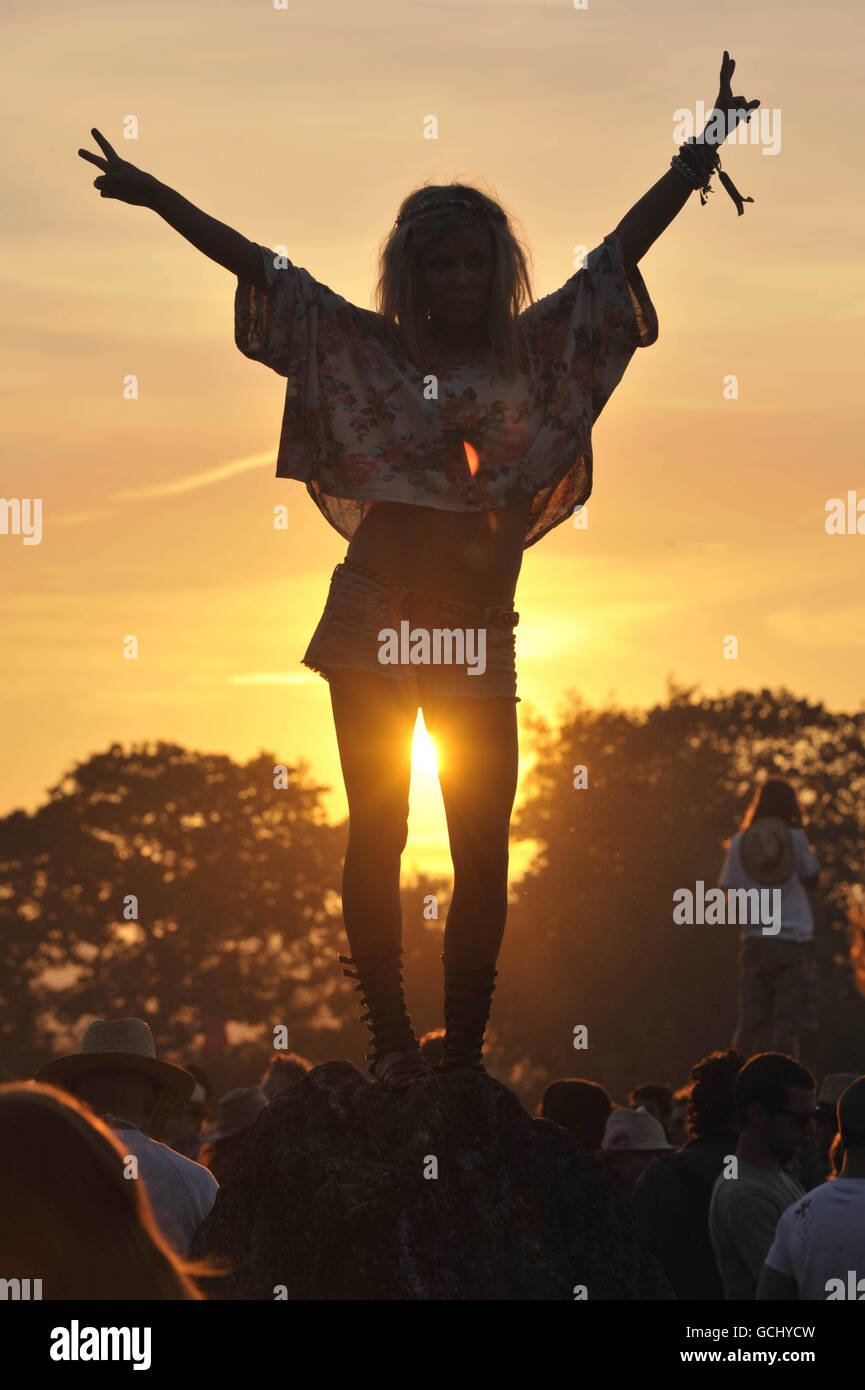 A reveller dances on top of a stone at the stone circle during a magnificent sunset at Glastonbury Festival 2010, Worthy Farm, Pilton, Somerset. Stock Photo