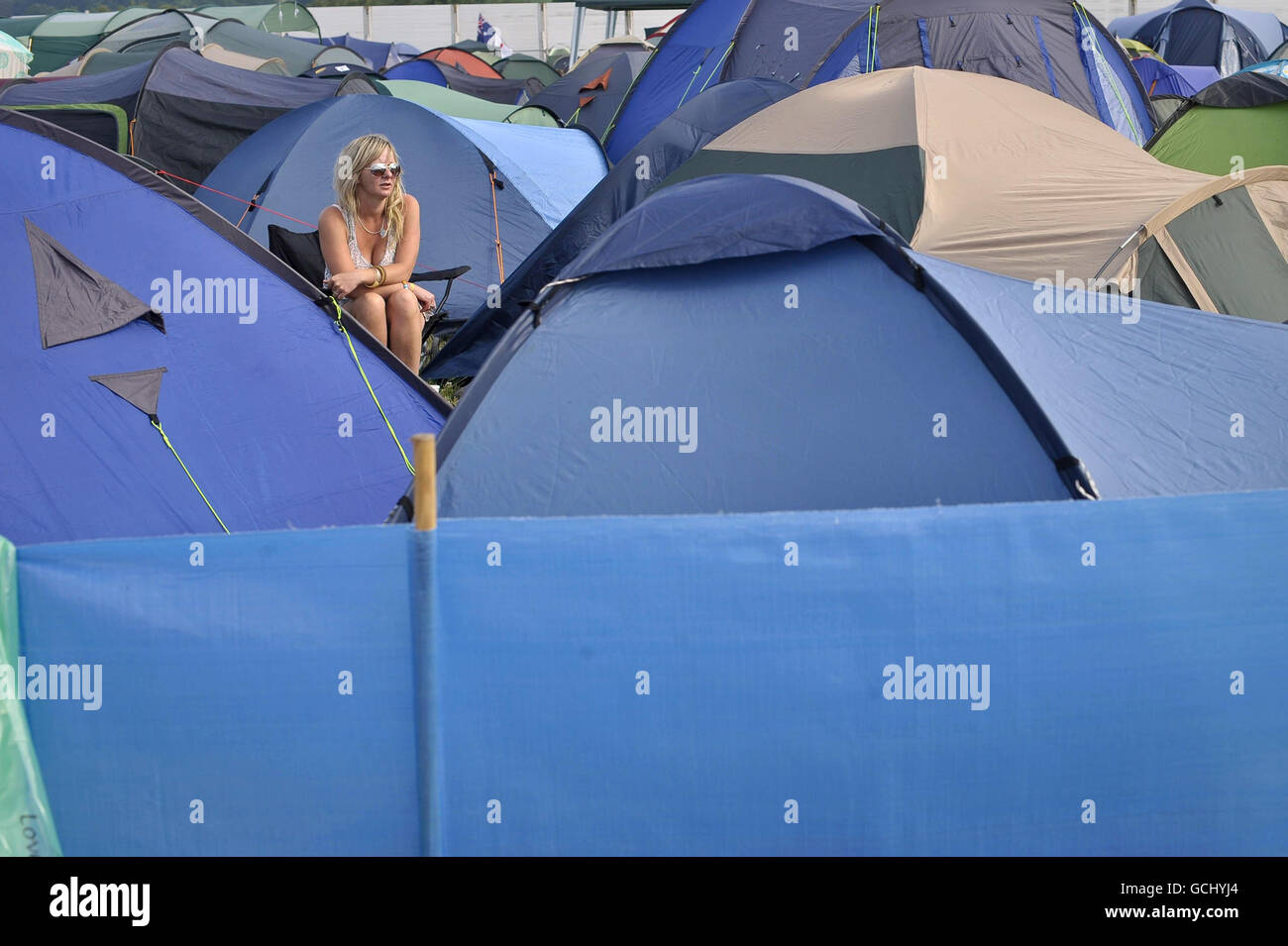 A festival goers sits amongst tents at Glastonbury Festival 2010, Worthy Farm, Pilton, Somerset. Stock Photo