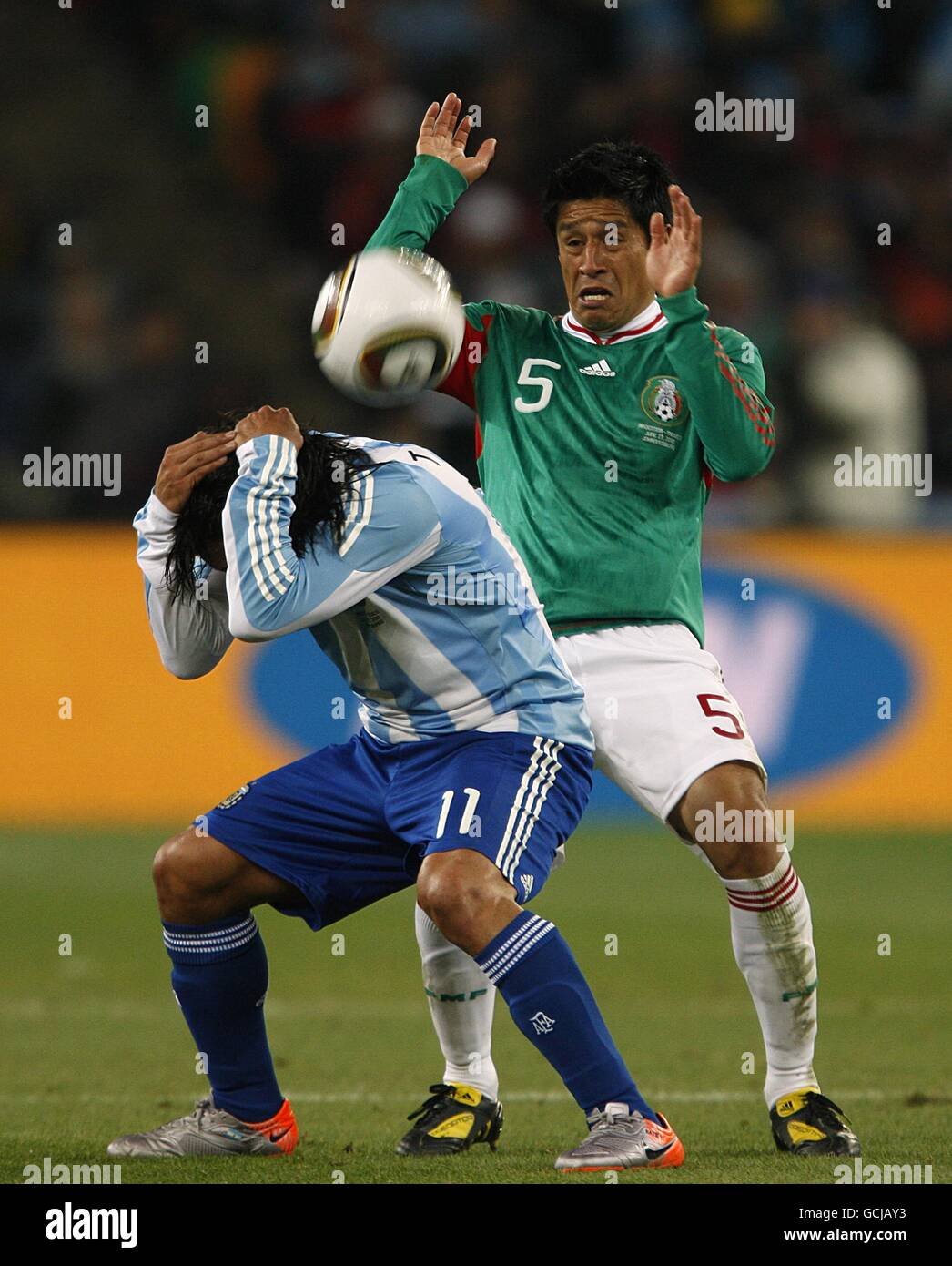 Soccer - 2010 FIFA World Cup South Africa - Round Of 16 - Argentina v Mexico - Soccer City Stadium. Argentina's Carlos Tevez holds his head in his hands as he battles for the ball with Mexico's Ricardo Osorio Stock Photo