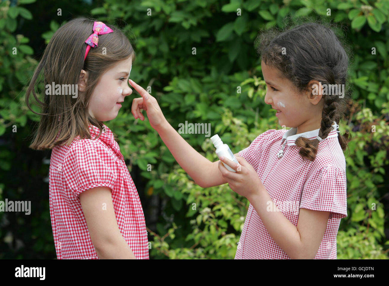 Molly (left) and Maiya from St Mary's and St Peter's Primary School in Teddington, Middlesex apply suncream as part of Nivea Sun's 'Buddy Up' campaign that helps children in primary schools learn about the importance of staying safer in the sun. Stock Photo