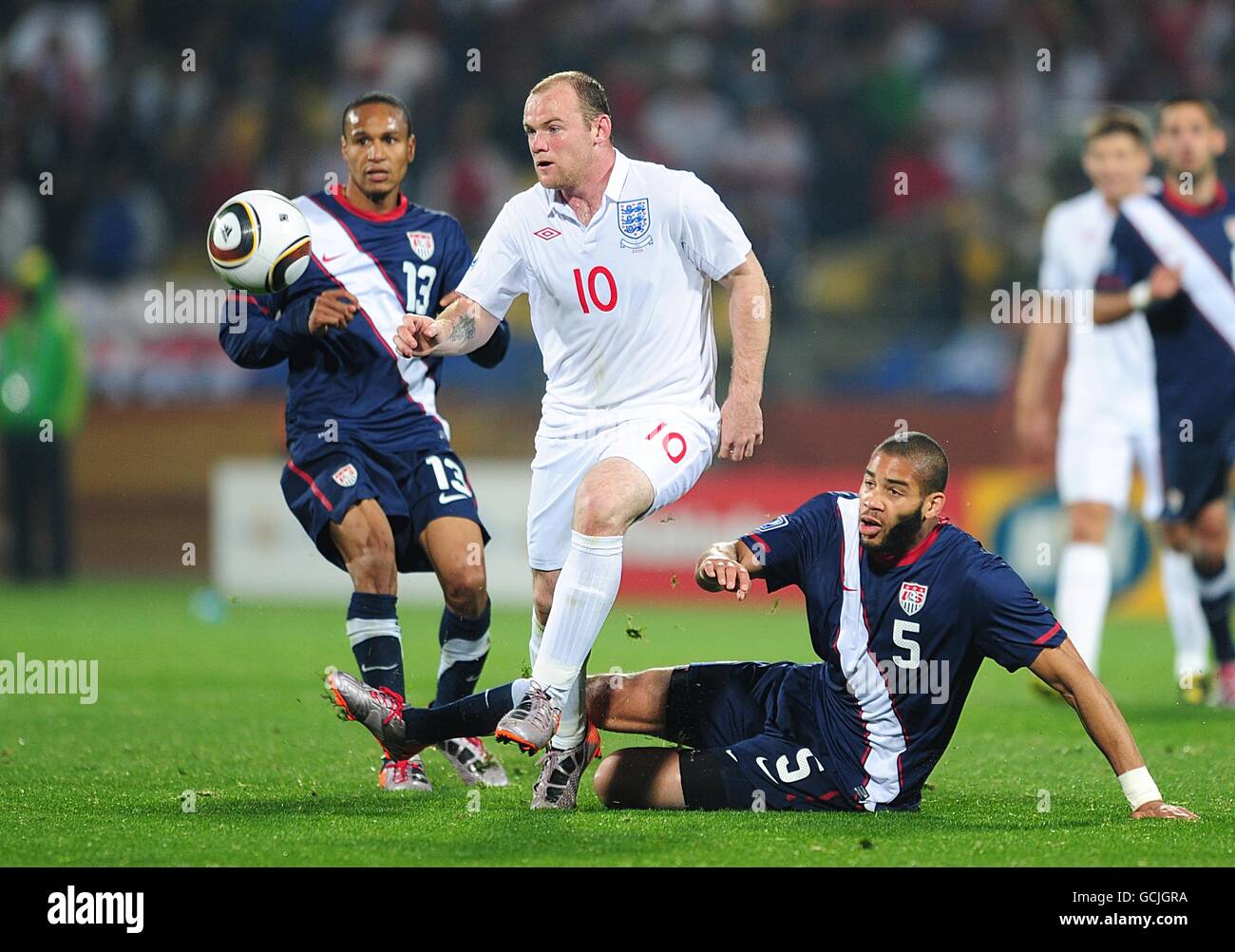Soccer - 2010 FIFA World Cup South Africa - Group C - England v USA - Royal Bafokeng Stadium. England's Wayne Rooney (centre) is challenged by USA's Oguchi Onyewu (right) for the ball Stock Photo