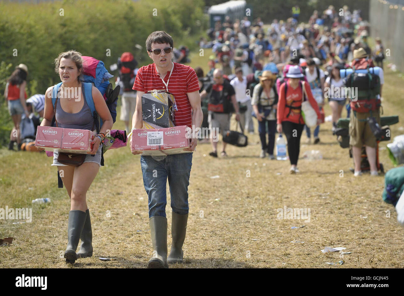 Revellers carry cider as they make their way into the Glastonbury Festival at Worthy Farm, Somerset. Stock Photo