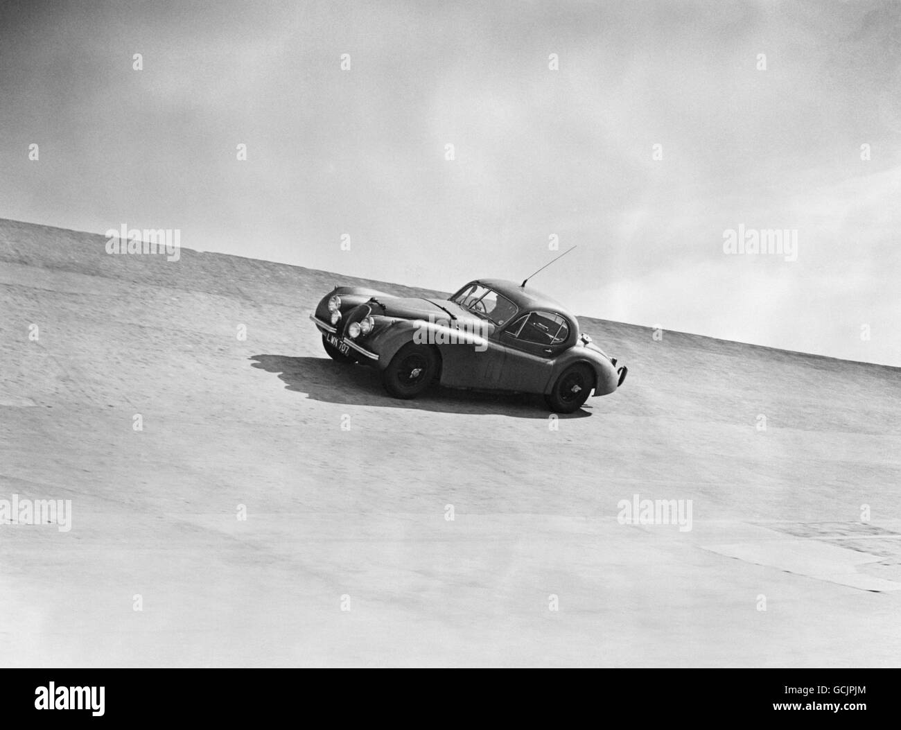 The XK 120 Jaguar, driven by Stirling Moss, speeds round the Montlhery track as he beats the world record at the 72nd hour race. At the wheel, driving in three hour shifts were Stirling Moss, Leslie Johnson, Herbert Hadley and Jack Fairman. Stock Photo