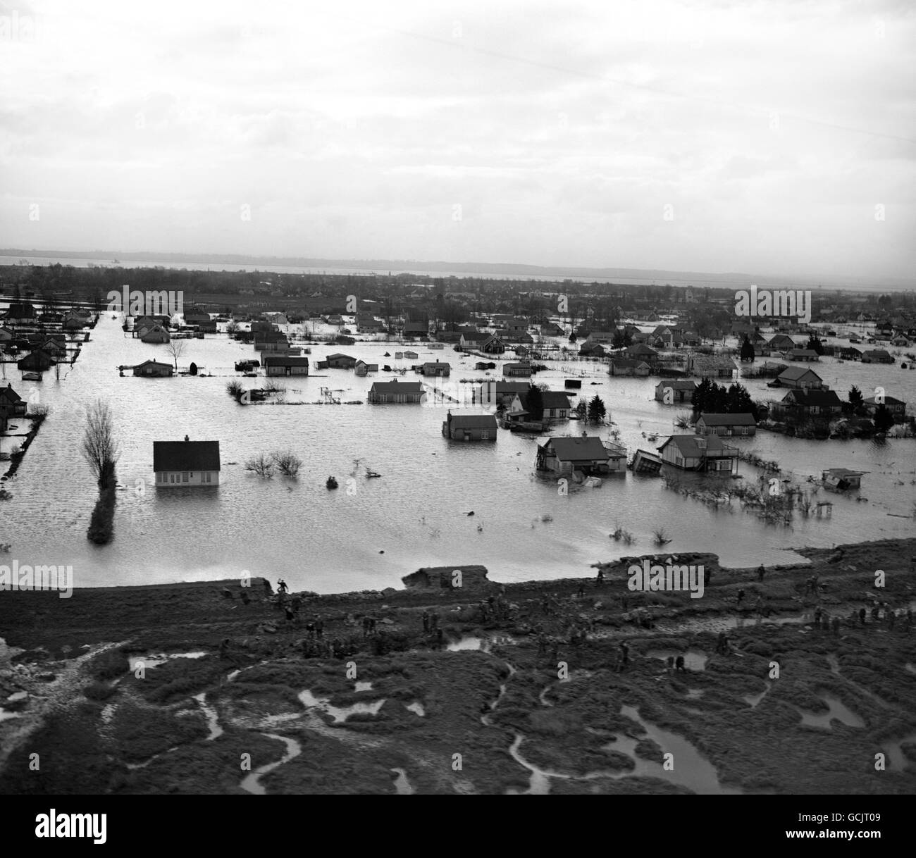SERVICEMEN ARE SEEN IN THIS AERIAL PICTURE WORKING ON THE SEA WALL, BREACHED IN SEVERAL PLACES, OF FLOODED CANVEY ISLAND, THE THAMES ESTUARY BUNGALOW HOLIDAY RESORT OVERWHELMED IN THE FLOOD DISASTER ALONG BRITAIN'S EAST COAST. AT LEAST 100 HAVE DIED. Stock Photo