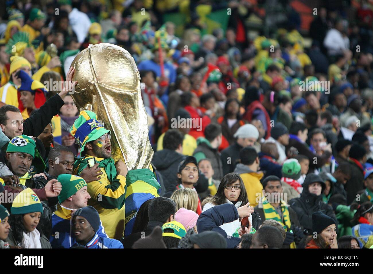 A fan of Brazil with a large replica of the world cup trophy in the stands. Stock Photo
