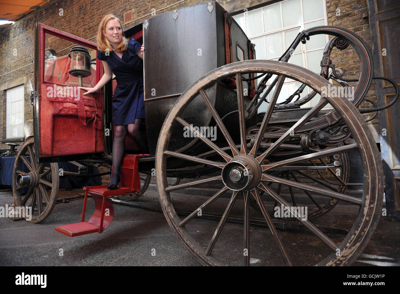 Charlotte Alport of Christies gets out of a state chariot owned by Lord and Lady Spencer in the late 19 century and will be offered for sale by Christies as part of a sale from the Althorp carriage collection and a wider sale of art, from the stables, cellars and storerooms at Althorp. The carriage pictured is expected to fetch 50,000 - 80,000. Stock Photo