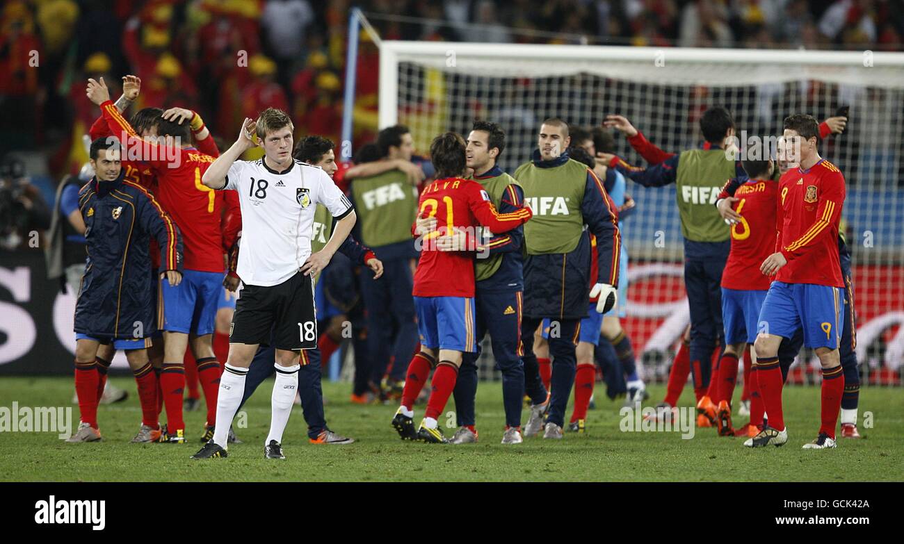 Germany's Toni Kroos (18) stands dejected as Spain players celebrate victory after the final whistle Stock Photo