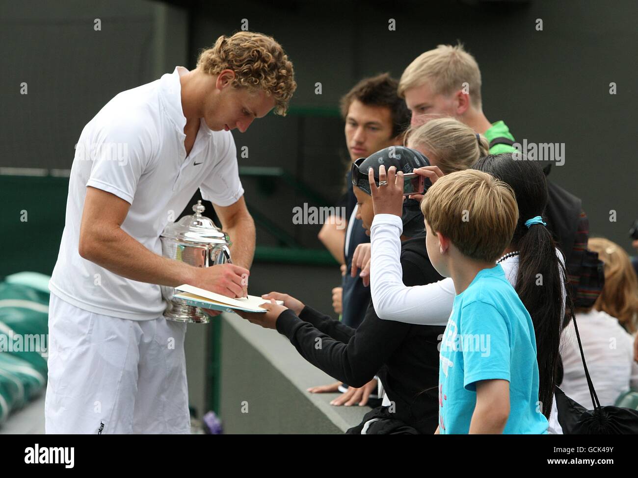 Great Britain's Tom Farquharson (left) signs autographs with his trophy tucked under his are after winning the Boy's Doubles Final with his tennis partner Liam Broady . Stock Photo