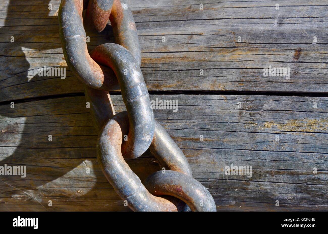Closeup abstract of rusted chain link draped against a wooden post. Stock Photo