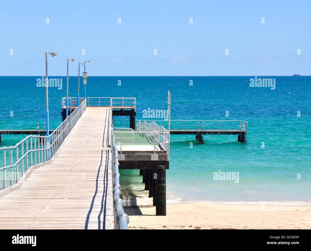 The Coogee Beach jetty structure with the turquoise-green Indian Ocean seasccape under a blue sky in Coogee, Western Australia. Stock Photo