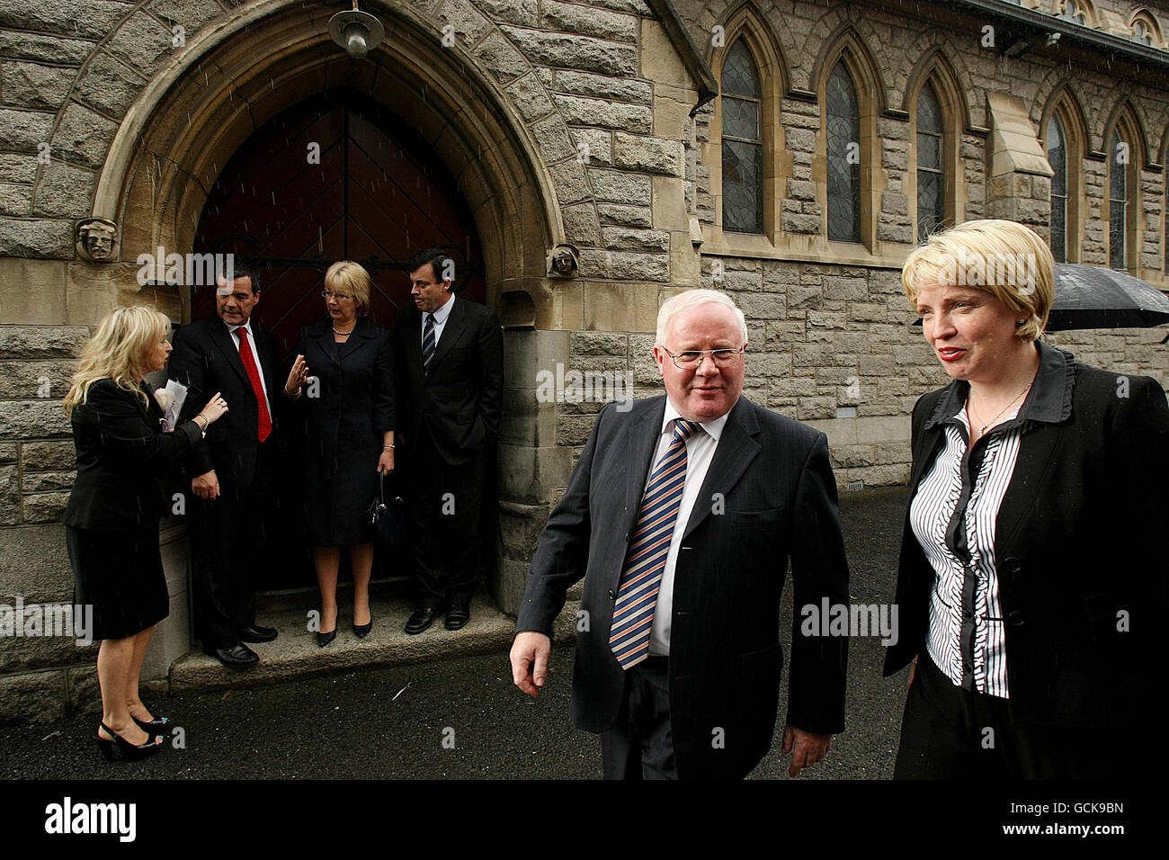 Minister for Transport Noel Dempsey (second left), Minister for Social and Family Affairs Mary Hanafin (third left) and Minister for Finance Brian Lenihan (fourth left) shelter in a dorrway from the rain as Tainaiste Mary Coughlan (right) walks past at the removal service for former Attorney General Rory Brady at the Church of the Sacred Heart, Donnybrook, Dublin. Stock Photo