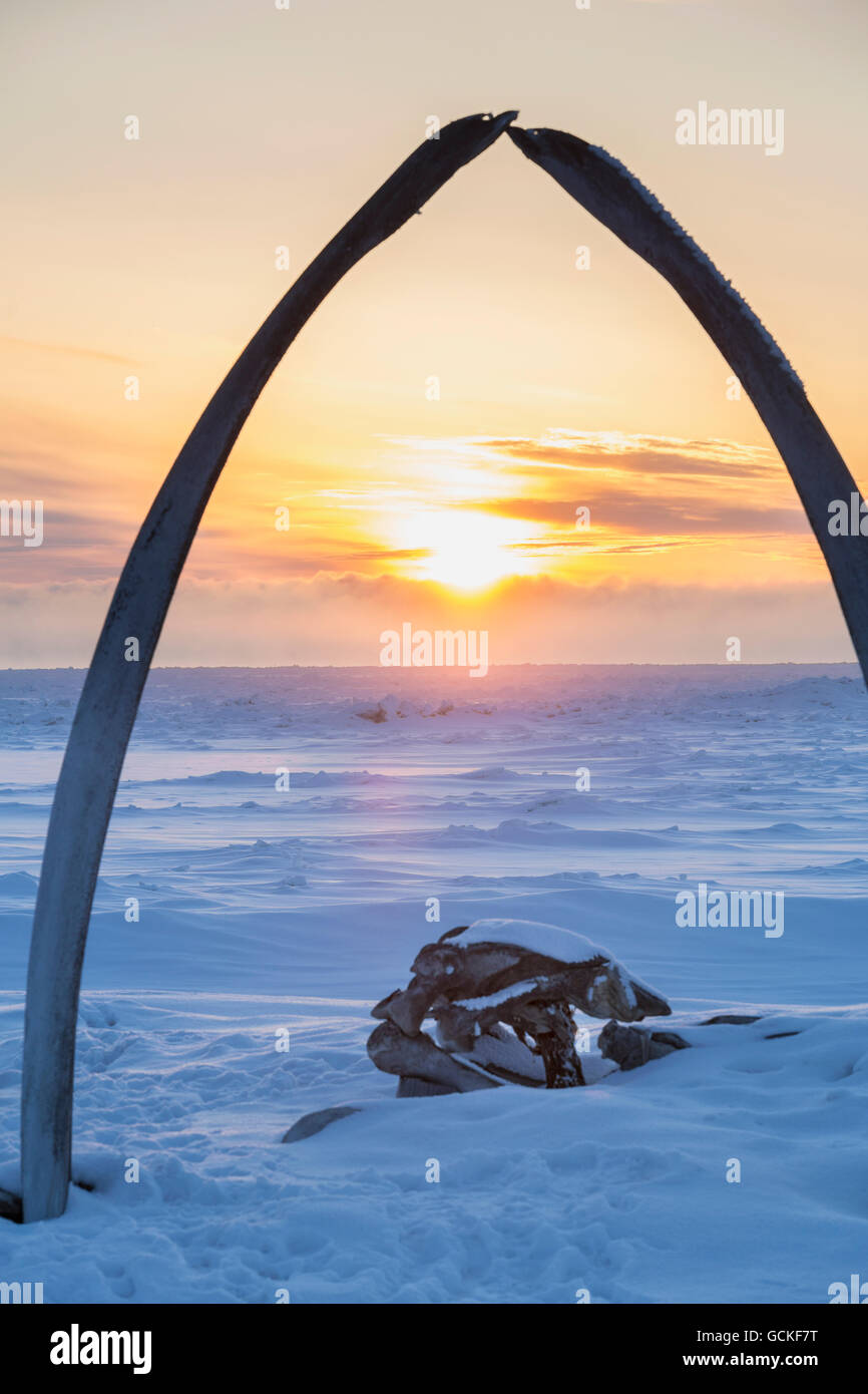 Whalebone arch frames the setting sun at the shore of the Arctic Ocean in Barrow, North Slope