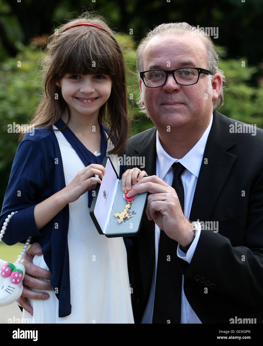 Composer Craig Armstrong and daughter Angeline, 8, holding his OBE after receiving it from Queen Elizabeth II at an Investiture at the Palace of Holyroodhouse in Edinburgh. Stock Photo