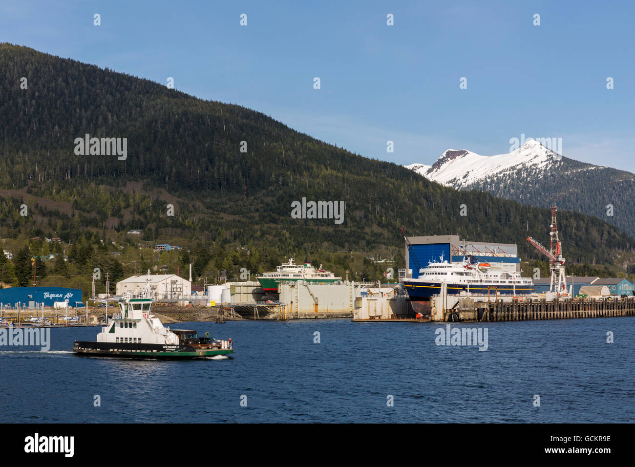 Airport passenger ferry passes in front of the waterfront docks and shipyards, Ketchikan, Southeast Alaska, spring Stock Photo
