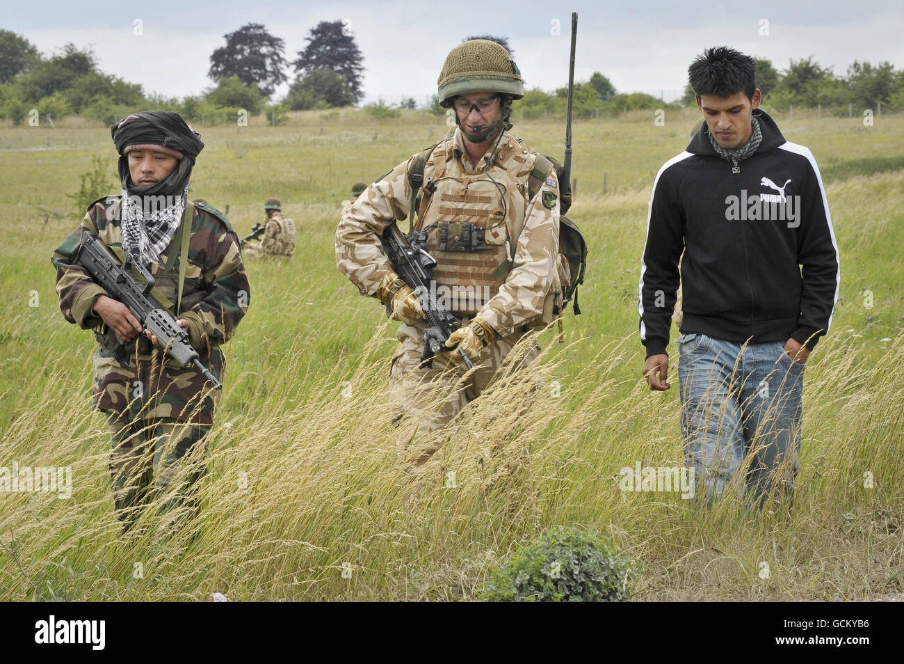 A soldier from 16 Air Assault Brigade (centre) alongside a retired Gurkha (left) simulating the role of Afghan National Army (ANA) and a man playing the role of an interpreter during a training exercise on Salisbury Plain. Stock Photo