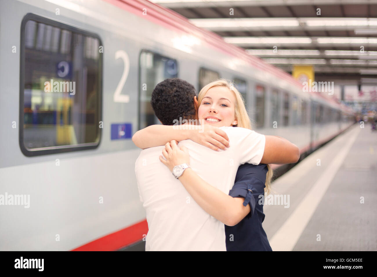 Interracial couple hugging at the train station Stock Photo