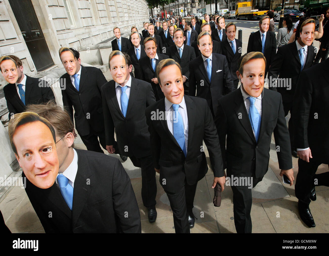 Protestors from Compassion in World Farming dress as clones of Prime Minister David Cameron, walk down Whitehall, in Westminster, London, as part of a demonstration against cloning animals for food production. Stock Photo