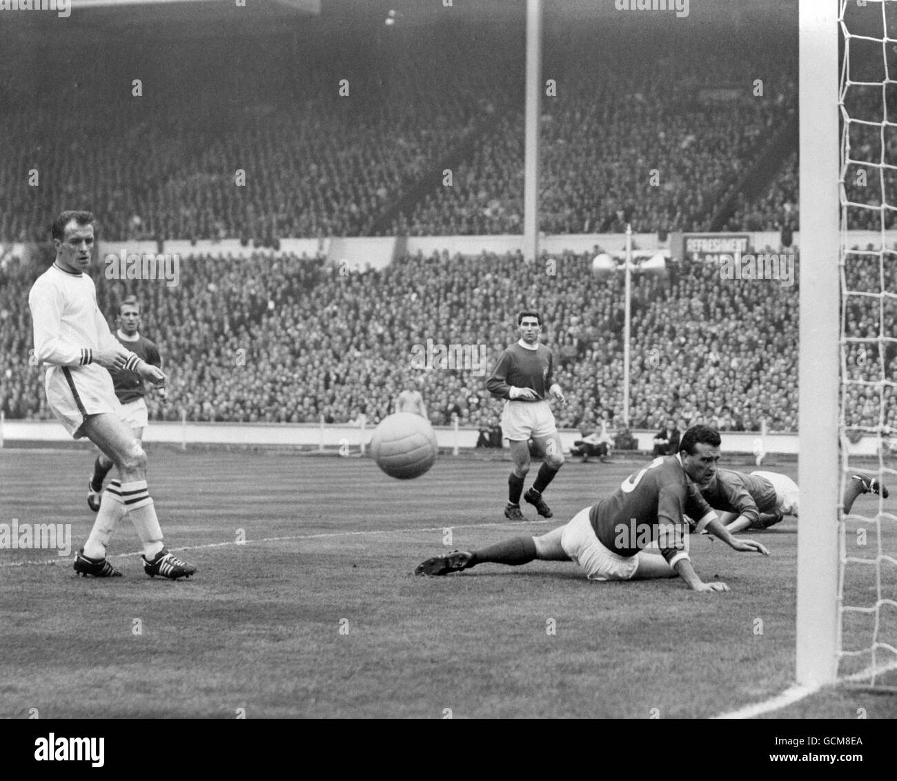 Manchester United's Noel Cantwell (on floor) watches the ball fly narrowly wide of his own goal after getting a slight touch on a cross. Watching, left, is Leicester City's Ken Keyworth. Stock Photo