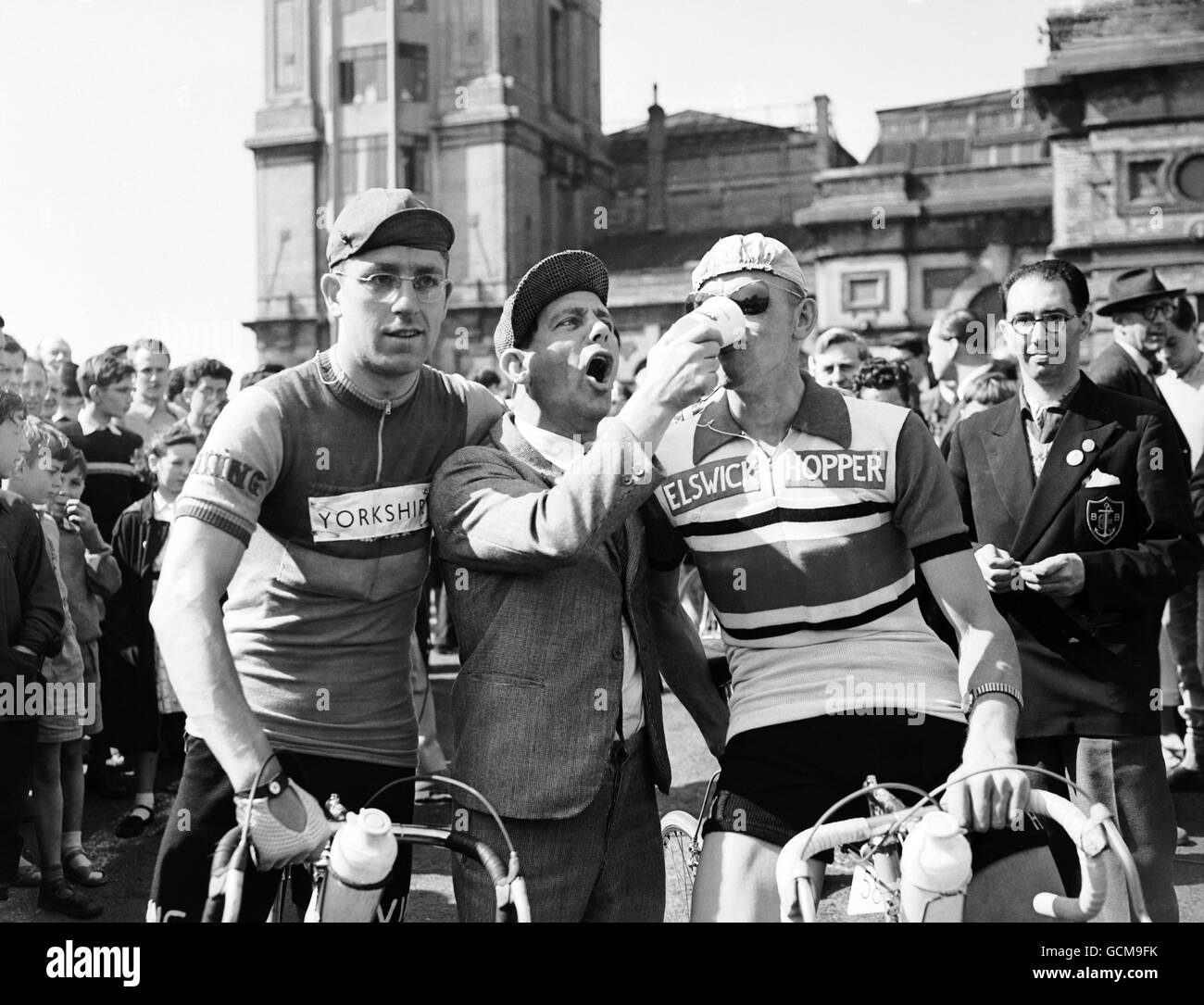 Norman Wisdom feeds milk to Sidney Wilson of Sheffield, who is riding for the north Midland team watched by Robert Eastwood of Huddersfield riding for the Yorkshire team prior to starting the race. Stock Photo