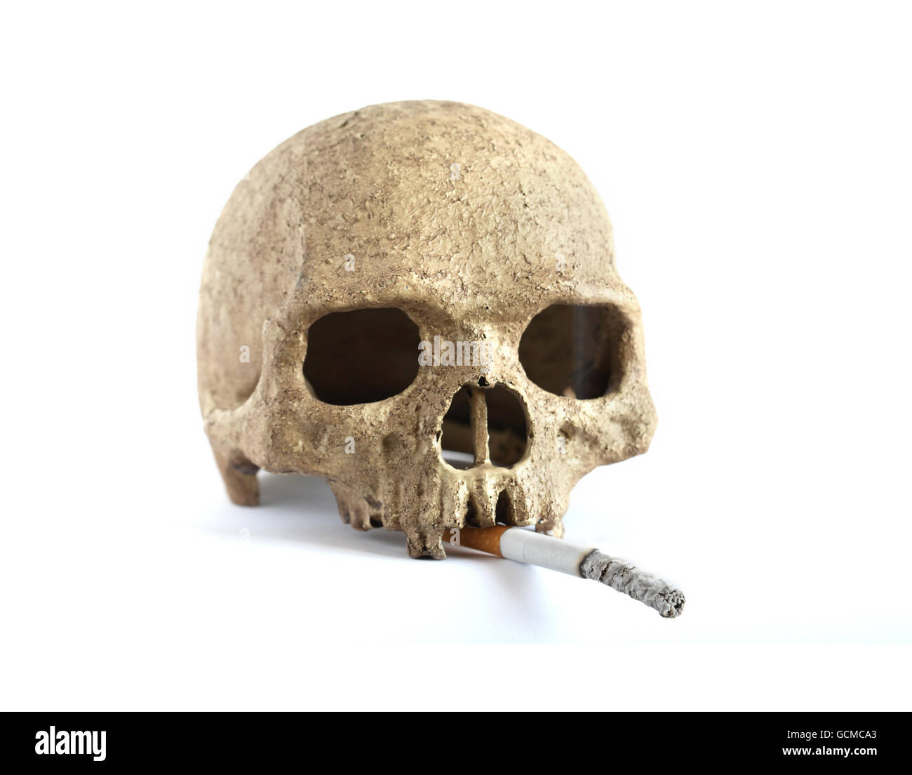 Human skull with smouldering cigarette on white background Stock Photo