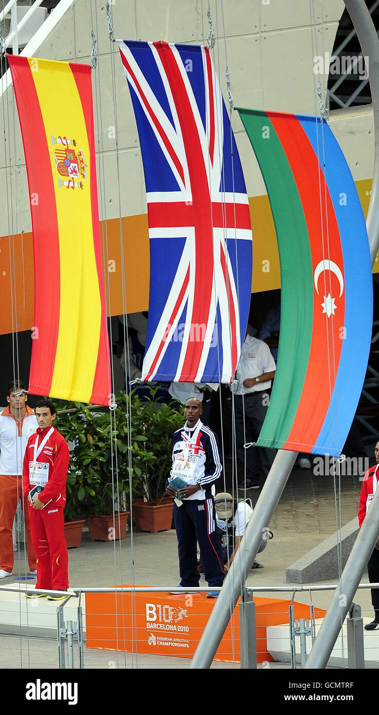 Great Britain's Mo Farah (centre) stands on the podium as the Union Flag is raised as he receives his second gold medal for his victory in the 5000m Race during day six of the European Championships at the Olympic Stadium in Barcelona, Spain. Stock Photo