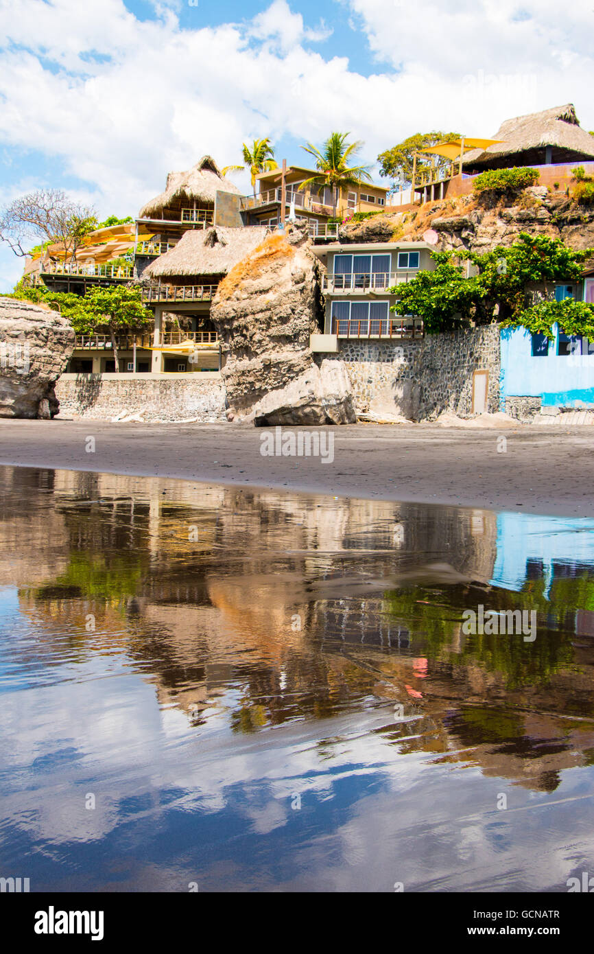 Sevral houses built into the rocks alongside the beach at El Salvador Stock Photo