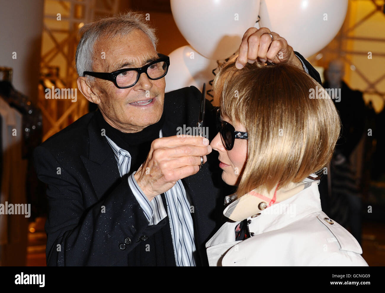 Vidal Sassoon pretends to cut the hair of an Anna Wintour look-a-like at Selfridges, as part of British Vogue's Fashion's Night Out, in London. Stock Photo