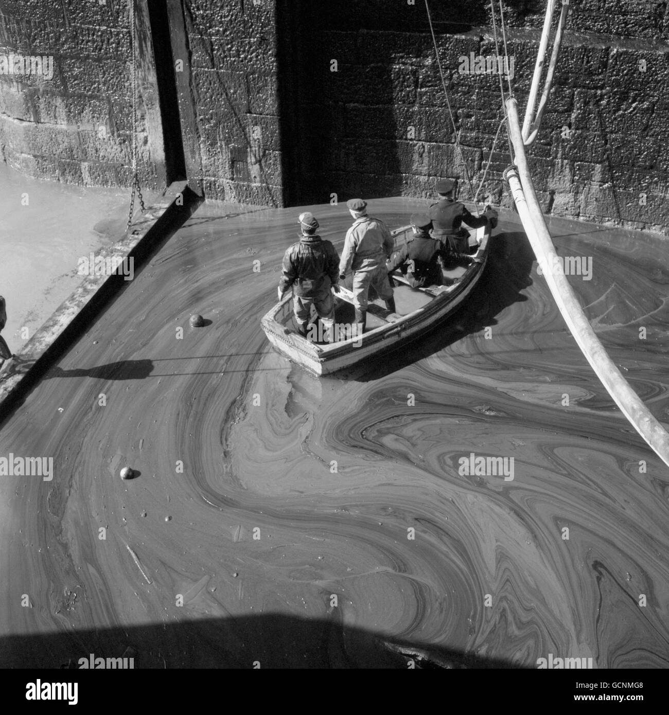 Disasters - Torrey Canyon Oil Tanker Spill - Cornwall. Firemen and fishermen surrounded by thick swirling oily sludge in a rowing boat at Porthleven, Cornwall. Stock Photo