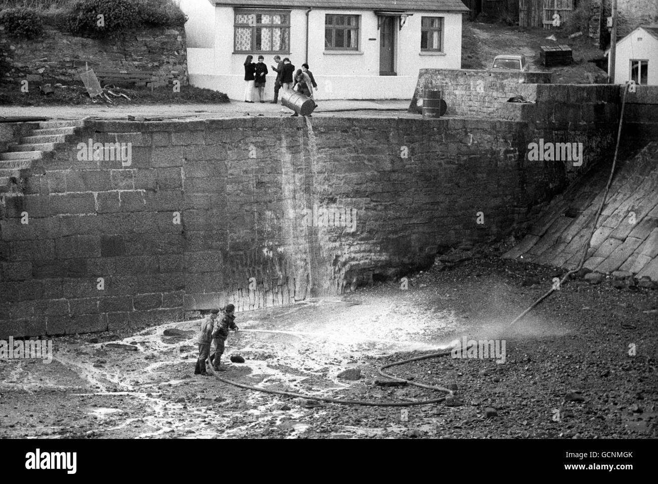 Oil from the tanker Torrey Canyon glistens on rocks as troops spray detergent at the small beach and bathing area of Dollar Cove in the Cornish hamlet of Gunwalloe. Stock Photo