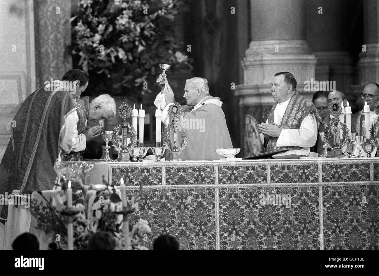 Pope John Paul II raises the chalice in the company of praying Cardinal Basil Hume (2nd Left), during the ceremony at Westminster Cathedral Stock Photo