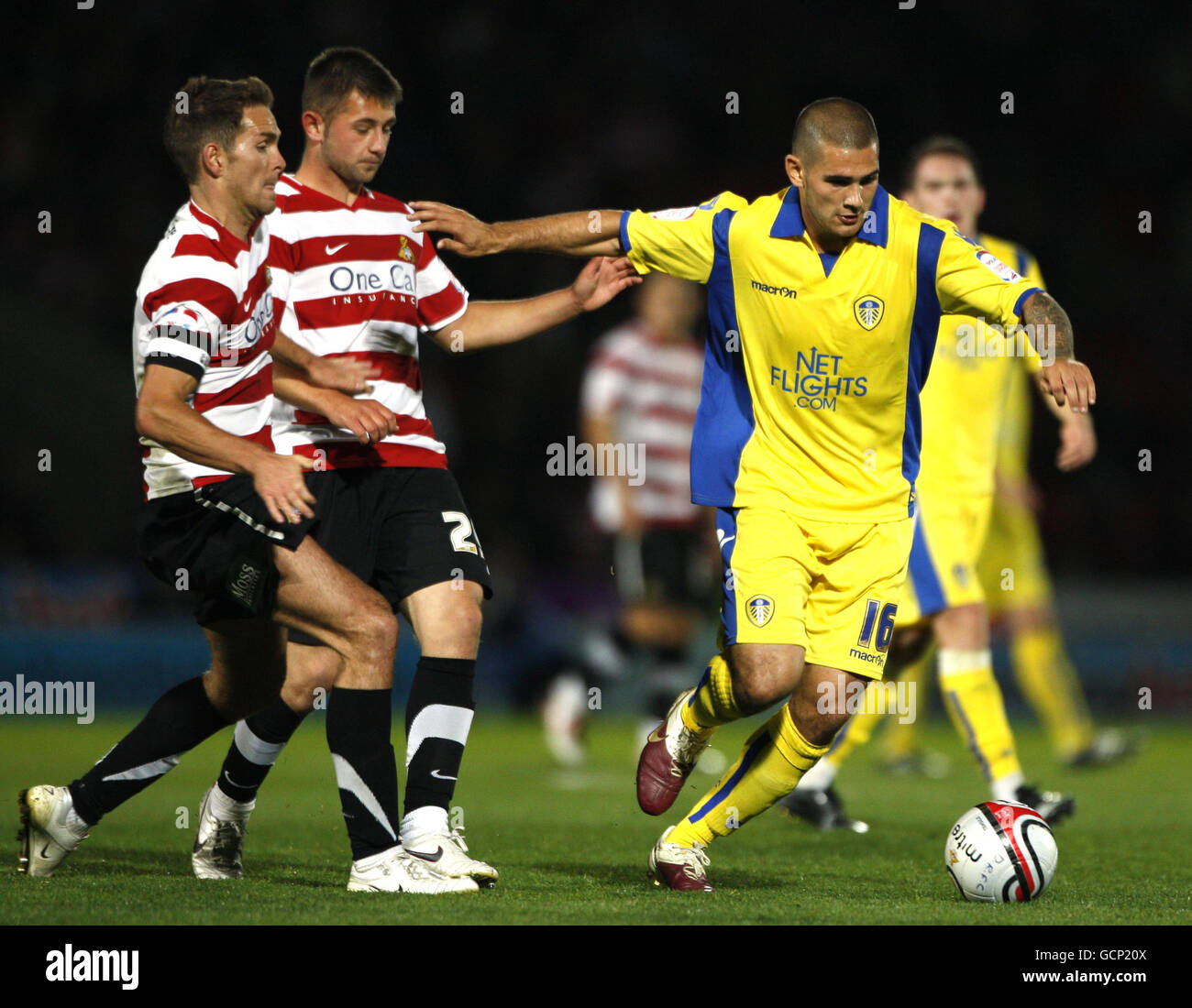 Leeds United's Bradley Johnson (right) holds off Doncaster Rovers Martin Woods (left) and Waide Fairhurst during the npower Football League Championship match at the Keepmoat Stadium, Doncaster. Stock Photo