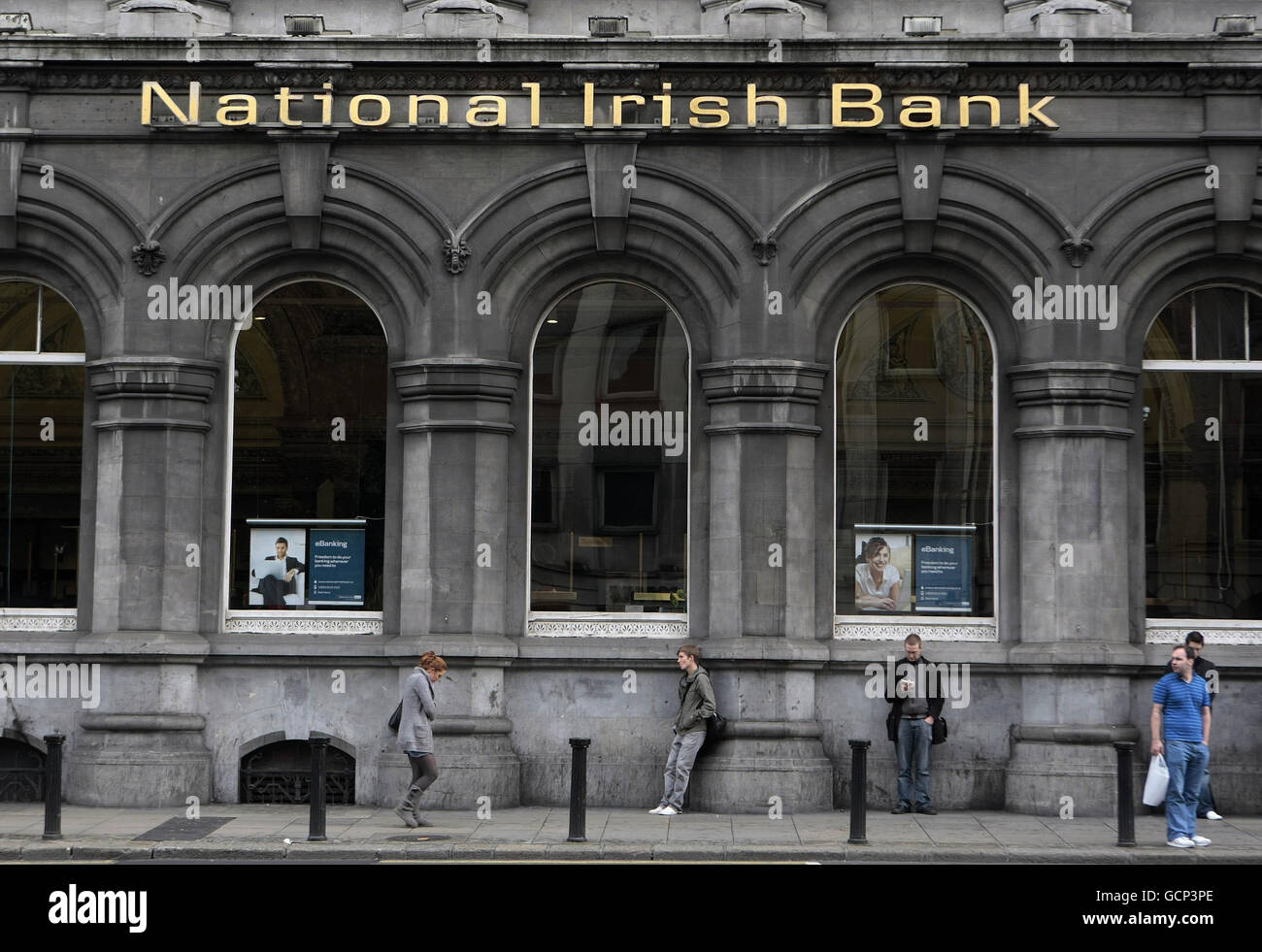 Members of the public standing outside the National Irish Bank in Dublin, as Irish Taoiseach Brian Cowen insisted today that people must start spending more cash as he dismissed claims that Ireland was heading for a double-dip recession. Stock Photo